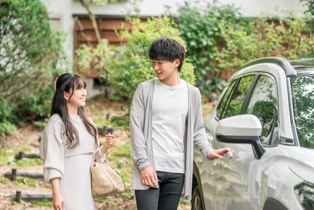 車のそばで話すカップル。レンタカーでドライブデート